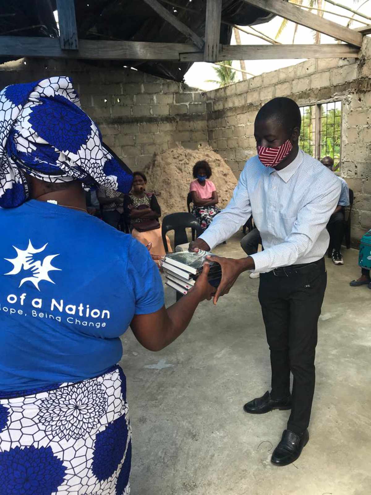 Amina, a Hope of a Nation team member, handing Bibles to a believer during a church gathering