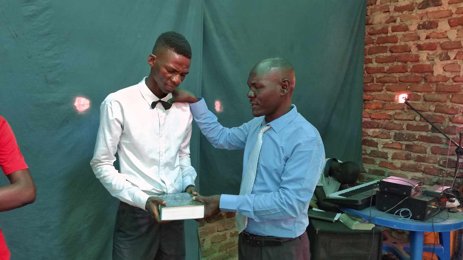 Pastor Abel praying over a young man as he receives his own Bible in Mozambique