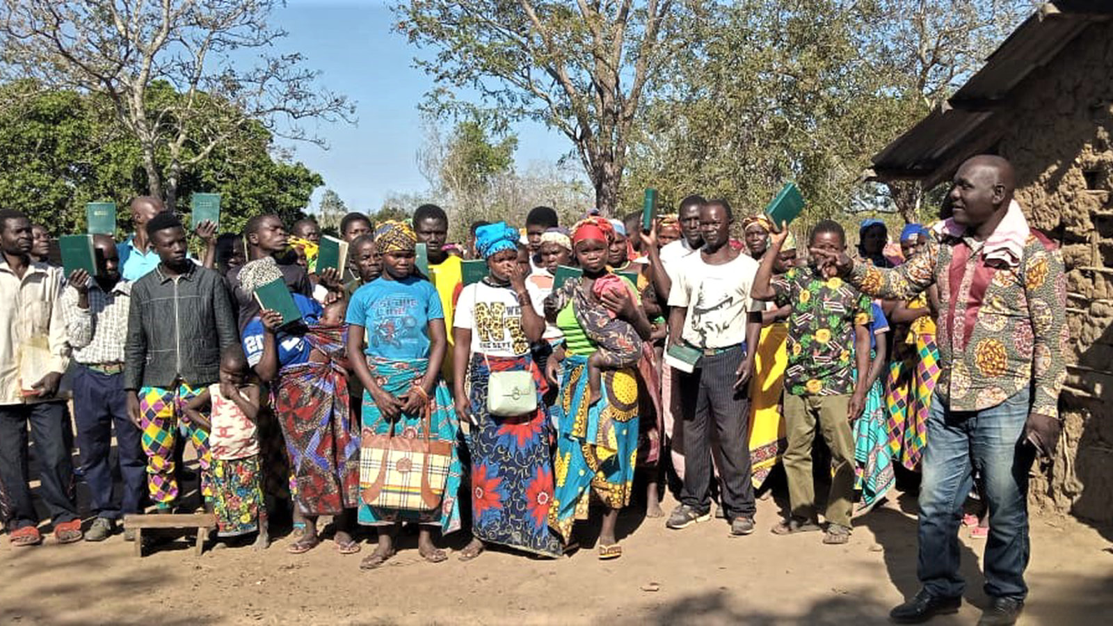 Abel with villagers holding up their new Bibles at a remote rural village in Nampula Province, Mozambique