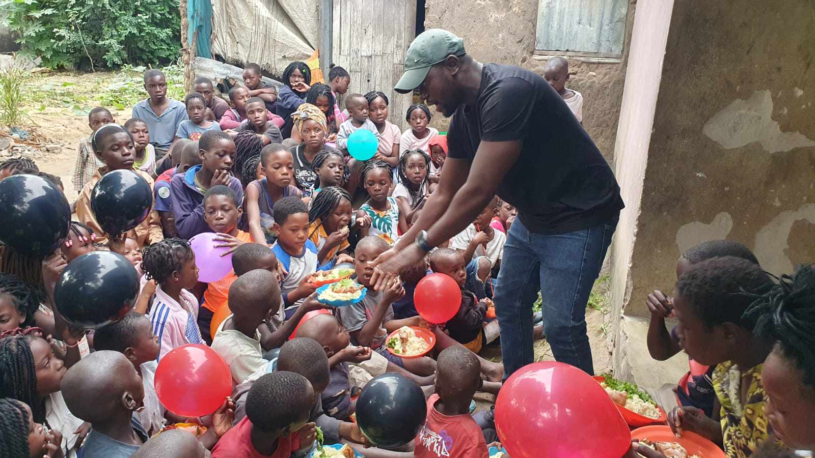 Children's Director Tony Gonondo handing out plates of food to hungry children at a weekly children's ministry gathering in Mozambique.