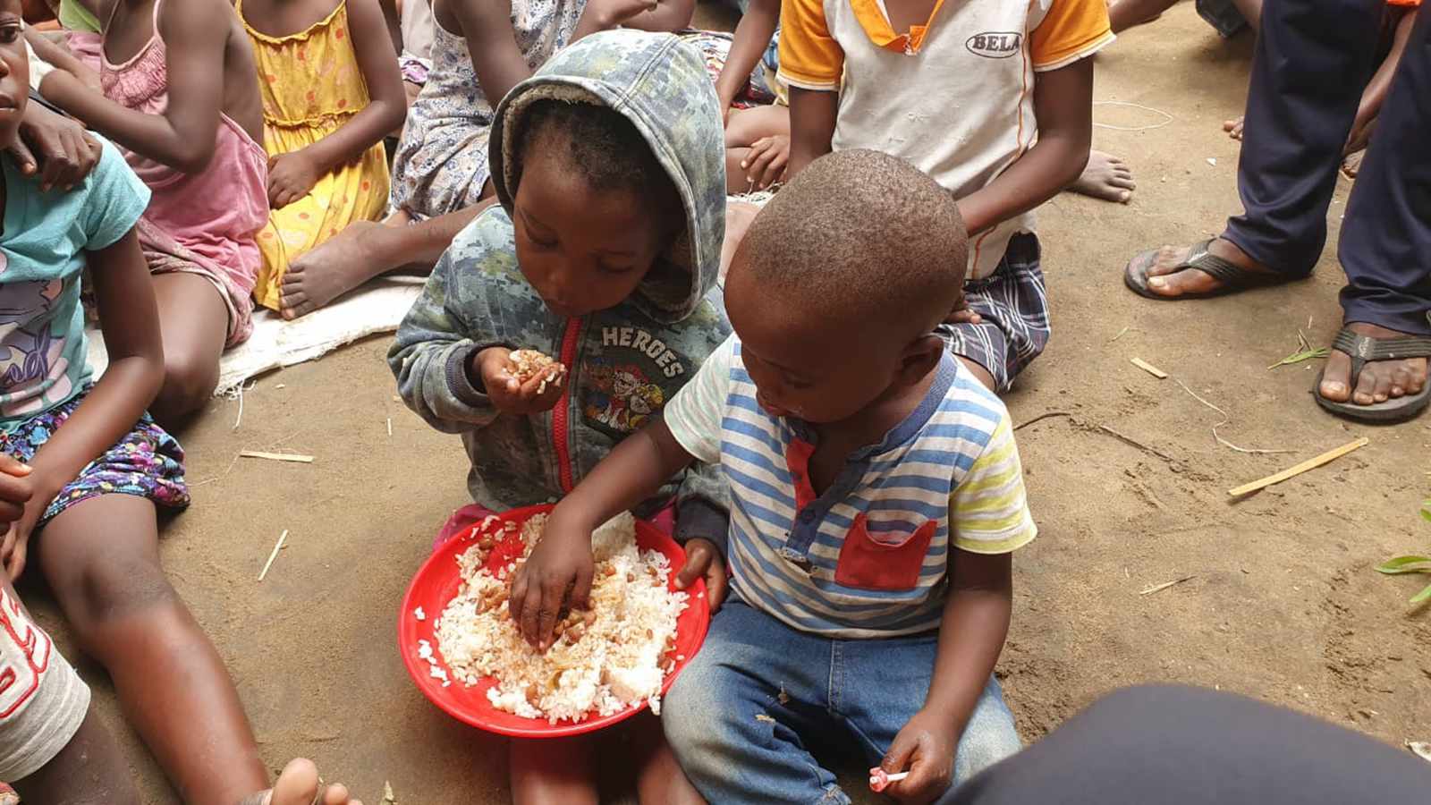 Children smiling and sharing a meal at a weekly gathering in Mozambique
