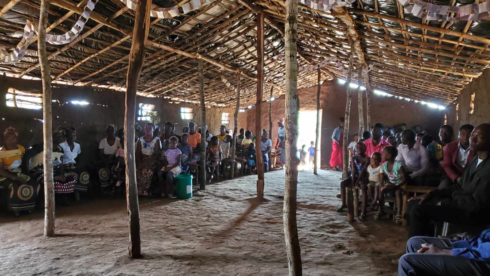A congregation gathered for worship inside a rural pole-and-thatch church in Mozambique
