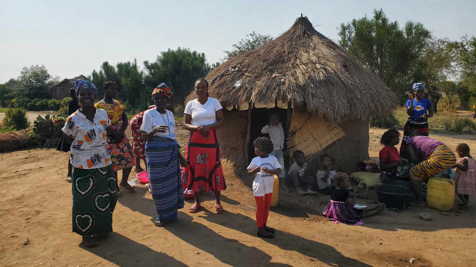 Women and children gathered outside a thatched-roof home in a Mozambican village