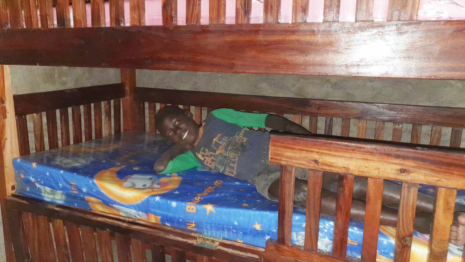 One of our boys smiles as he lays on the bottom bunk of a new bed he now shares with his brother - the first beds they've ever had.