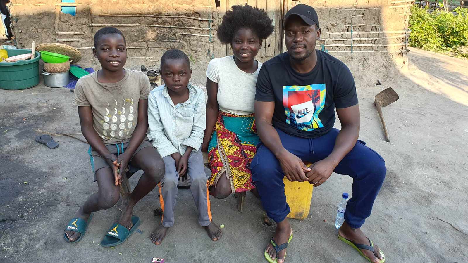Children's Services Director Tony Gonondo sitting with three of our children during a home visit in Mozambique.